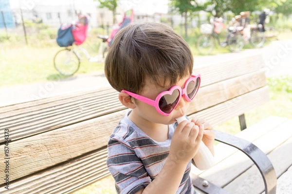 Obraz ハートのサングラスをかけた男の子がスイーツを楽しむ夏の屋外ポートレート｜家族レジャー・お祭りイメージに最適な子ども写真