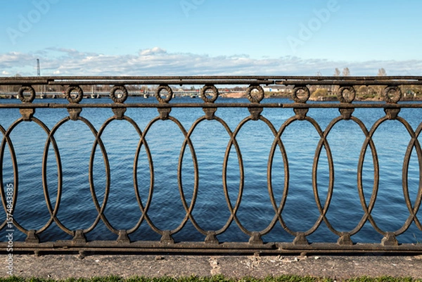 Fototapeta Decorative cast iron fence installed on the embankment in the city of Vyborg.