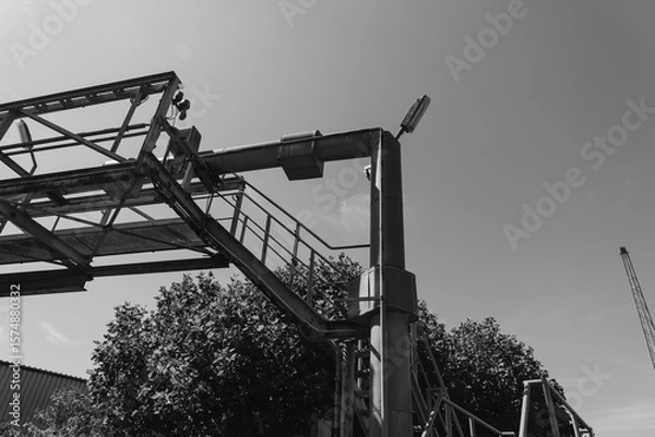 Fototapeta Sturdy construction framework rises against a bright sky while a crane looms in the background during a sunny afternoon