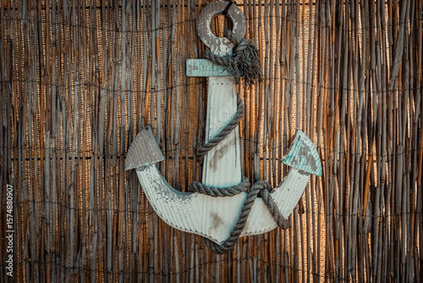 Fototapeta Rustic anchor adorned with frayed rope against a woven backdrop creates an inviting coastal atmosphere in this charming nautical decor