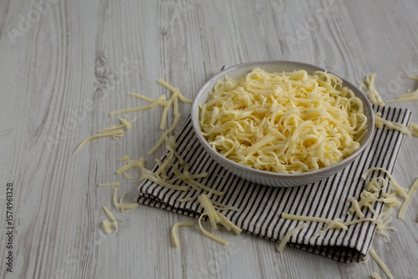 Fototapeta Organic Shredded Mozzarella Cheese in a Bowl, side view. Copy space.