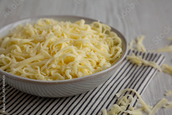 Fototapeta Organic Shredded Mozzarella Cheese in a Bowl, side view. Close-up.