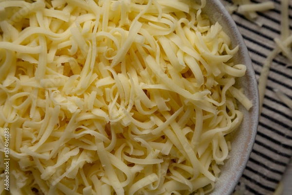 Fototapeta Organic Shredded Mozzarella Cheese in a Bowl, top view. Close-up.