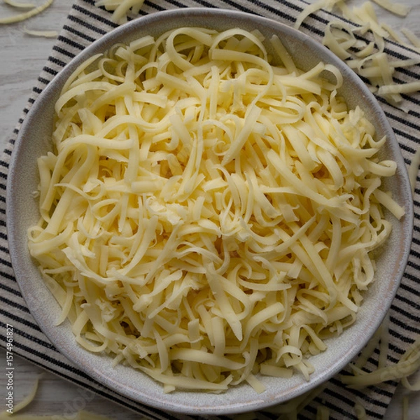 Fototapeta Organic Shredded Mozzarella Cheese in a Bowl, top view. Close-up.