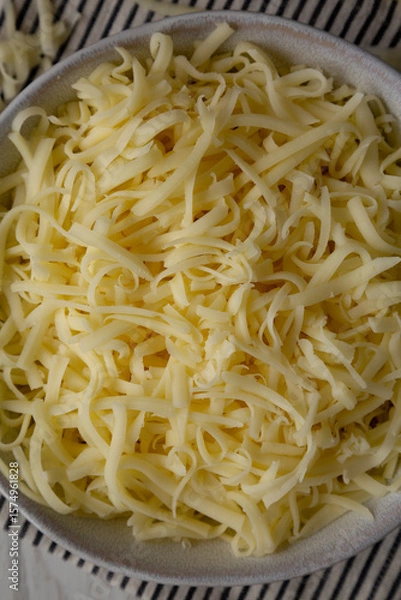 Fototapeta Organic Shredded Mozzarella Cheese in a Bowl, top view. Close-up.