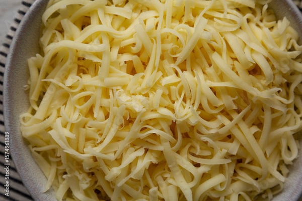 Fototapeta Organic Shredded Mozzarella Cheese in a Bowl, top view. Close-up.