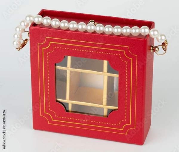 Obraz Elegant red box purse with pearl strap displaying intricate design details