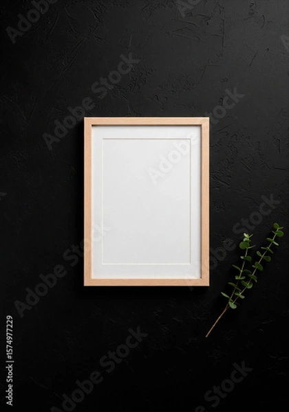 Fototapeta Blank wooden frame mockup with green branch on black background for art prints, branding or minimalist interior visuals