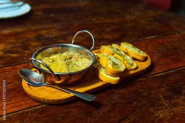 Fototapeta Creamy dip served with garlic bread on a wooden platter, perfect for sharing and enjoying.