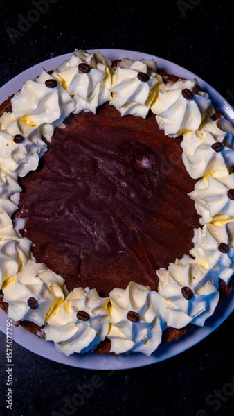 Fototapeta A decadent chocolate cake, adorned with creamy whipped cream and coffee beans, ready to be enjoyed.