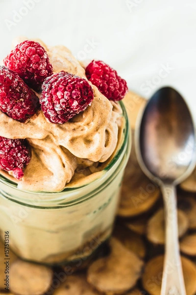 Fototapeta Chocolate banana ice cream, raspberries in a glass jar, close up.