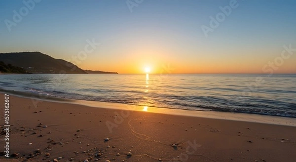 Fototapeta A beach scene featuring the sun setting over the ocean with a mountain in the distant background view