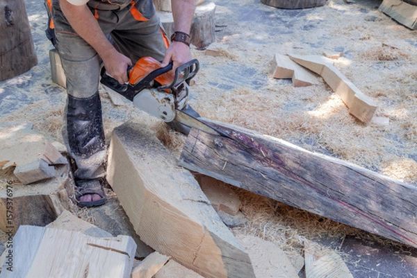 Obraz Man is cutting wood with a chainsaw