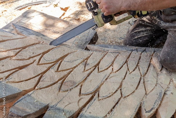Obraz Man is cutting a piece of wood with a saw