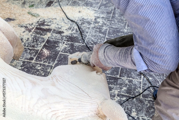 Obraz Man is carving a wooden sculpture with a power tool