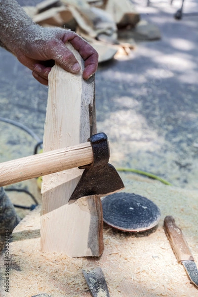 Obraz Man is using an axe to cut a piece of wood