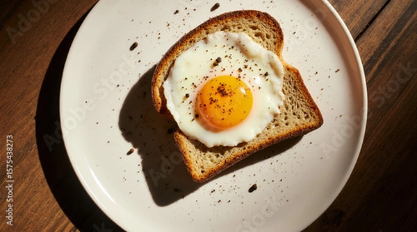 Fototapeta Delicious fried eggs on toast, seasoned with pepper, served on plates in a rustic, home-style presentation. AI generated.