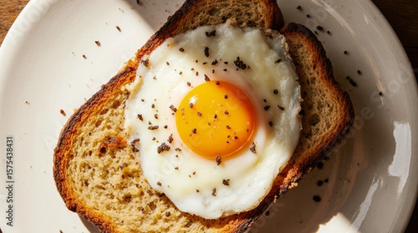 Fototapeta Delicious fried eggs on toast, seasoned with pepper, served on plates in a rustic, home-style presentation. AI generated.