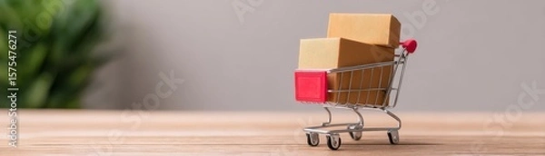 Fototapeta Seamless E-Commerce Transactions with Secure Payment Gateway Solutions, A miniature shopping cart with cardboard boxes on a wooden surface, symbolizing online shopping and delivery.