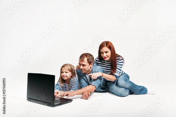 Fototapeta Happy family Father, mother and child lying on the floor with laptop on white background isolated