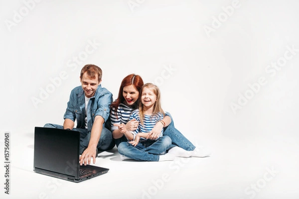 Fototapeta Happy family Father, mother and child lying on the floor with laptop on white background isolated