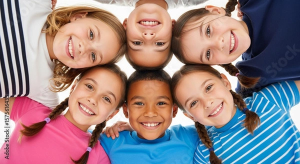Obraz A diverse group of six smiling children form a circle with their heads together, looking up