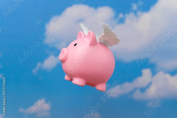 Obraz A piggy bank with small white wings flying against a blue sky. Symbolizes concepts related to money flying away, financial freedom, or the elusive nature of wealth.