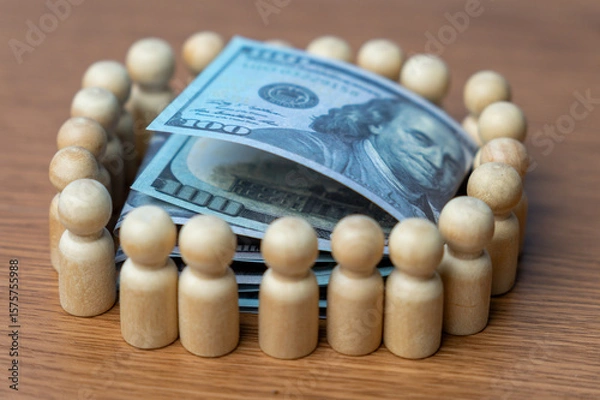 Obraz A stack of U.S. hundred-dollar bills surrounded by a wooden human figurines. Crowdfunding concept.