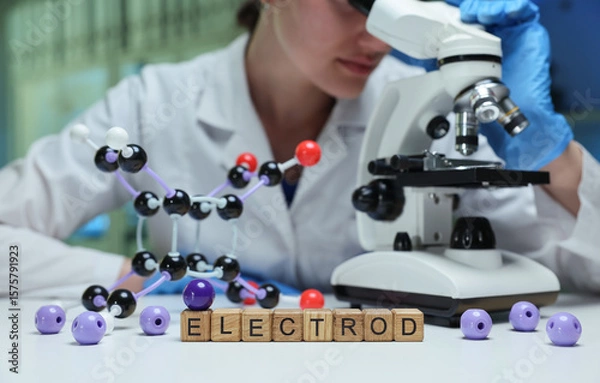 Obraz A researcher examines samples through a microscope in a laboratory setting, showcasing molecular models.