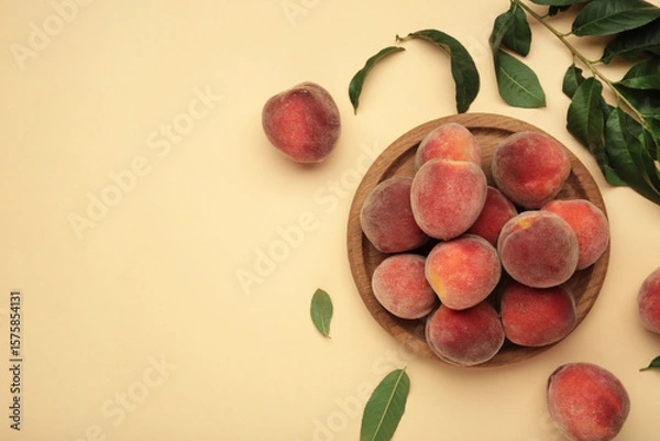 Obraz Sweet peaches and leaves on wooden plate on beige background. Space for text