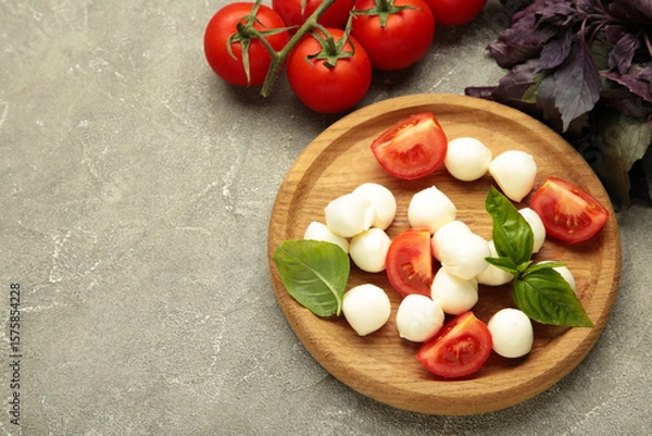 Obraz Italian Caprese salad with cherry tomatoes, mozzarella, basil on plate on grey concrete background. Space for text