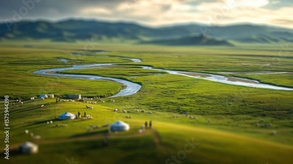 Fototapeta A panoramic view of a winding river meanders through a vast, lush green landscape, offering a sense of peace and serenity. There are some houses at the bottom of image