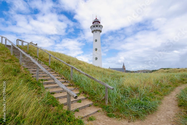 Obraz The J.C.J. van Speijk Lighthouse tower with european marram grass (beach grass) under blue sky in summer, Dutch north sea coastline, Egmond aan Zee, Municipality of Bergen, Noord Holland, Netherlands.