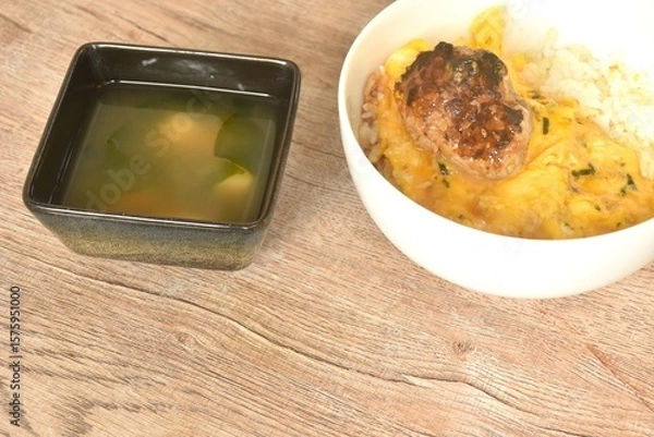 Obraz grilled hamburg pork steak and creamy egg omelets topping on rice in bowl with miso or soy sauce soup