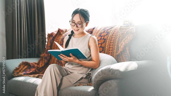 Obraz Beautiful young adult asian woman wearing eyeglasses reading book on sofa relax hobby routines
