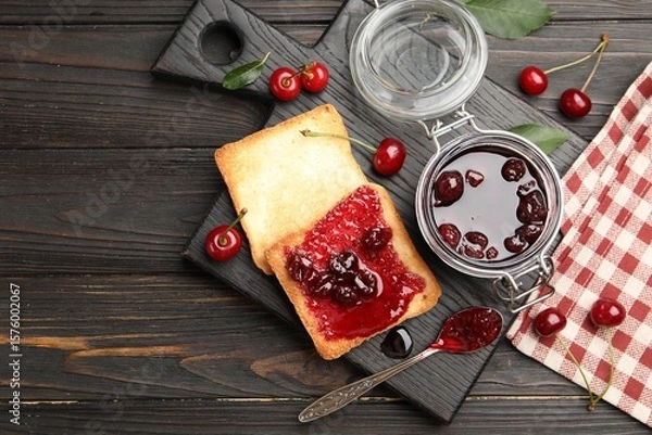 Fototapeta Toasts with tasty cherry jam and fresh fruits on black wooden table, flat lay