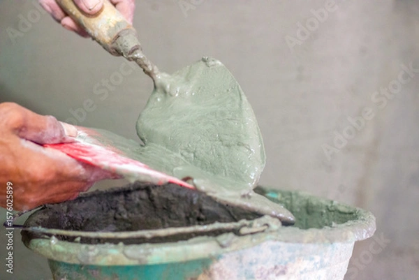 Obraz Hand holding cement mortar in tool