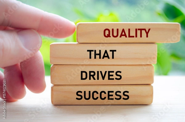 Fototapeta Quality that drives success text on wooden blocks being pushed forward symbolizes how excellence leads to real achievement