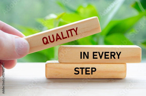 Fototapeta Quality in every step text on wooden blocks held carefully symbolizes continuous improvement and focus