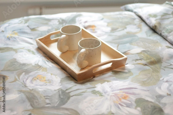 Fototapeta Cozy Morning in Bed with Floral Blanket and Two Mugs on Tray. Floral blanket and a wooden tray holding two ceramic mugs, perfect for coffee, tea, or a quiet moment shared. 