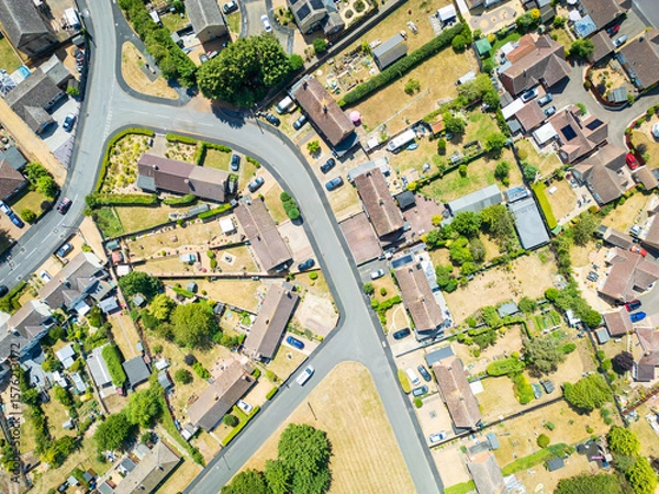 Fototapeta Aerial top down view of a parched lawns and vegetation seen in a town within the UK. Houses can be seen in rows along the empty street due to extreme summer weather of 2025.