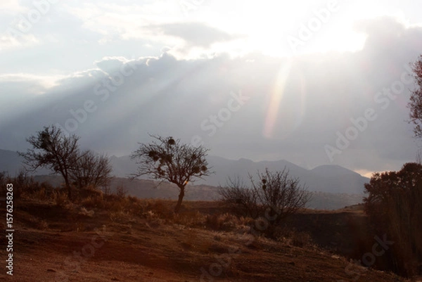 Obraz silhouette mountains, light beam through clouds