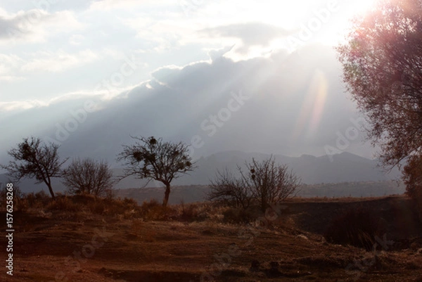Obraz silhouette mountains, light beam through clouds