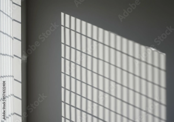 Obraz A pristine, minimalist light grey wall with strong, sharp geometric shadows from a rectangular window and vertical blinds, creating a bright copy space area. Concept of architectural light and shadow