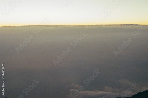Fototapeta A captivating view of a golden sky at dawn, hovering over a sea of clouds, presenting a serene and tranquil atmosphere. Perfect for inspiring themes of nature, peace, and breathtaking landscapes.