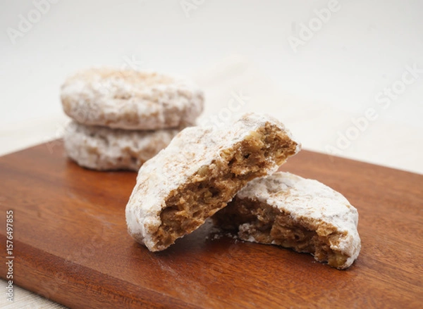 Fototapeta Delicious Mixed Nuts Cookie Dusted with Powdered Sugar broken in half to reveal its rich on Wood Board side view of sweet snack