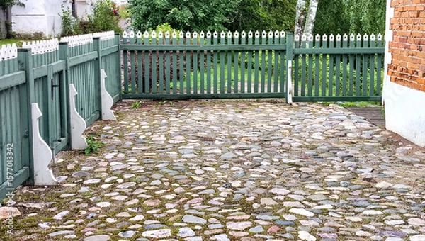 Fototapeta A neatly manicured farmyard, cobbled and enclosed by a wooden fence