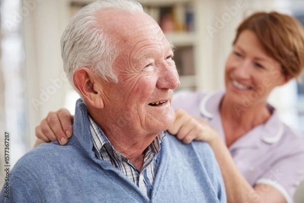 Obraz Smiling elderly man receiving a caring shoulder massage from a friendly female nurse in a cozy home setting.