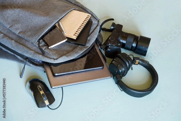 Obraz Urban backpack showcasing essential gadgets for tech-savvy individuals, including notebook, pen, and power bank for study or travel. Photo. High resolution