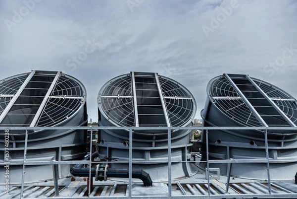 Fototapeta Cooling fans are installed on rooftop of large commercial building. Maintaining air circulation and temperature control. Tower air chiller HVAC.